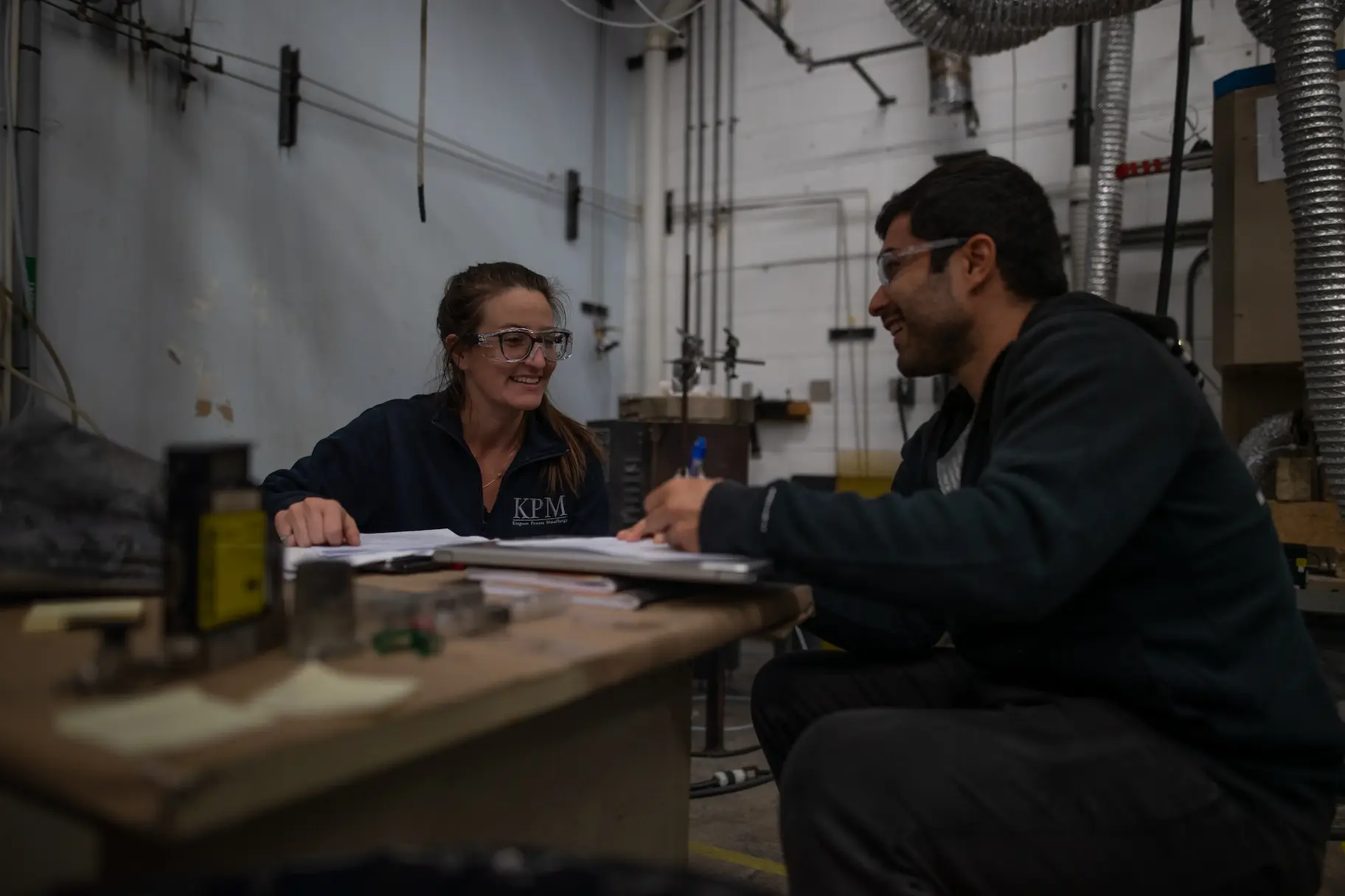 two people smiling at a shop workbench